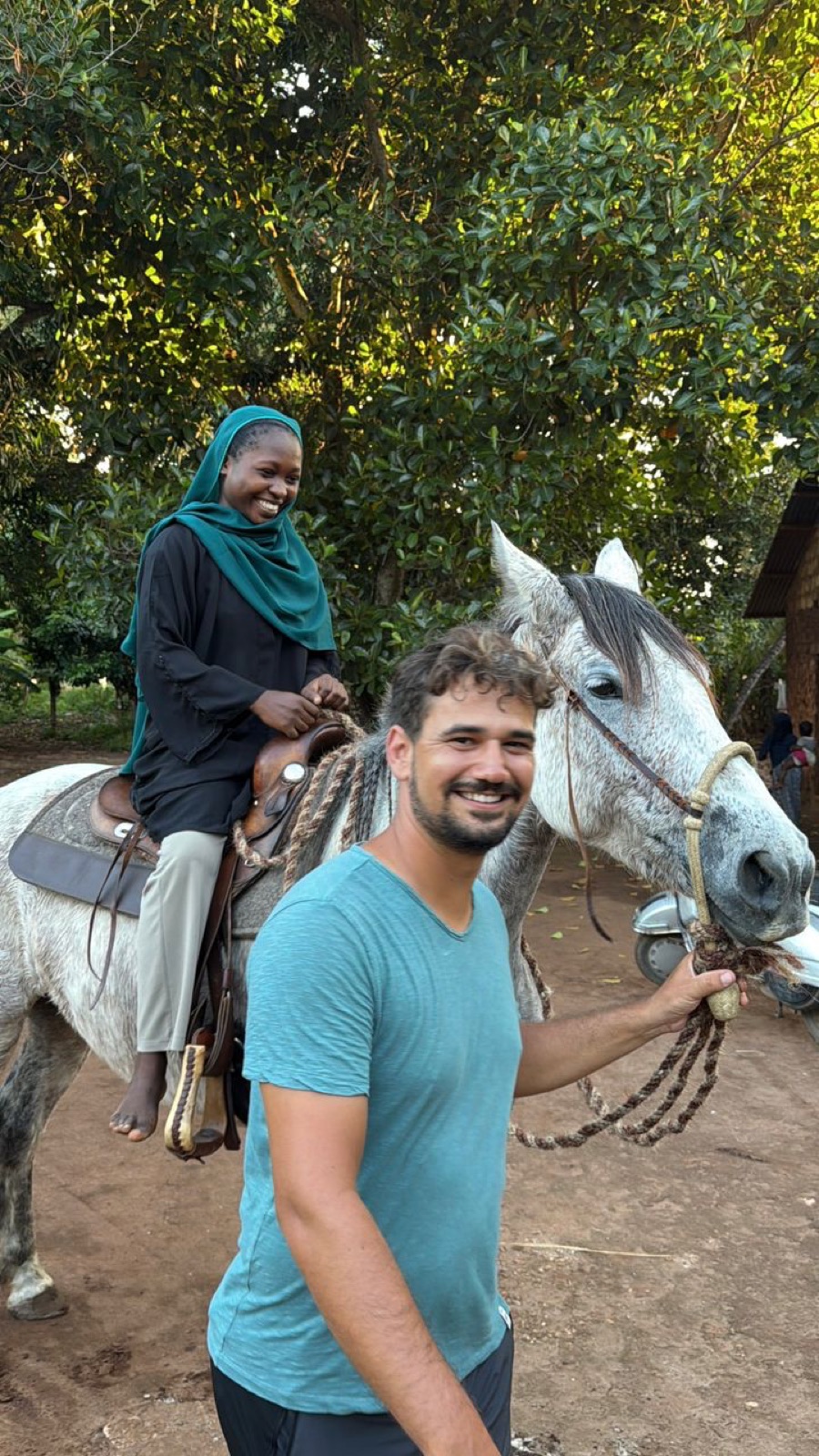 A girl riding a grey horse, smiling